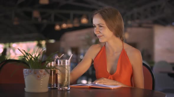 Lady Drinks Beverage Reads Diary at Cafe Table