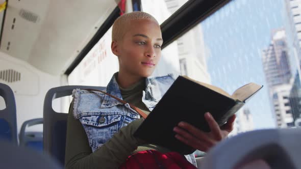 Mixed race woman taking the bus and reading a book