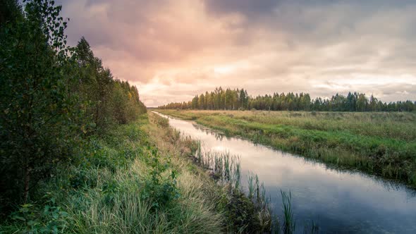 Cinemagraph of a slow river flowing as clouds form at sunrise in a seemless and endless time lapse