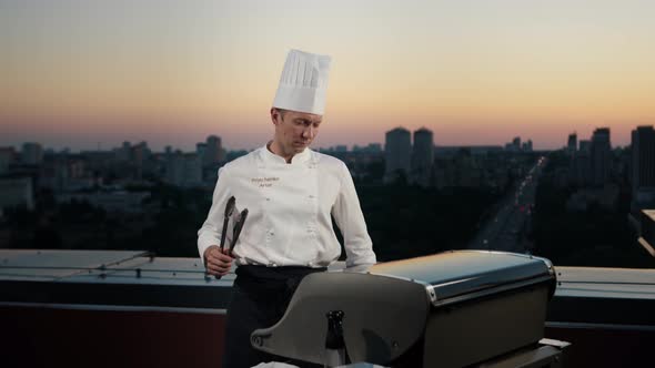 A professional Chef prepares a barbecue on the rooftop of a skyscraper. An expensive restaurant