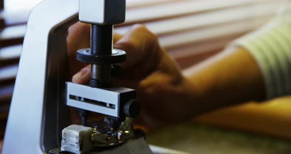 Horologist repairing a watch on a machine