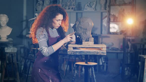 Lady Sculptor is Using a Scraper While Working with Clay