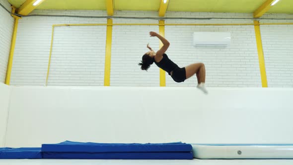 Black girl practicing back flips on mats in gym