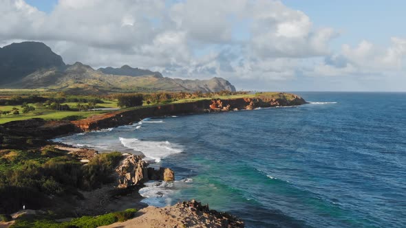 Aerial footage of ocean and rocky coast, mountains on the island and clouds in Kauai, Hawaii, USA