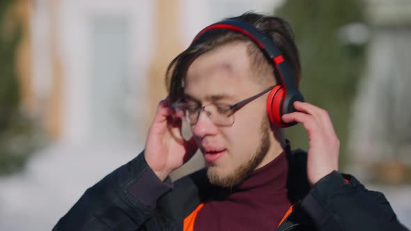 Closeup Portrait of Absorbed Excited Young Caucasian Man in Eyeglasses Enjoying Music in Headphones