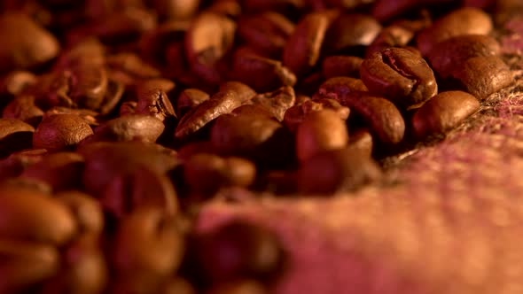Coffee Beans on Burlap Sacking Background with Purple Light, Rotation, Close Up