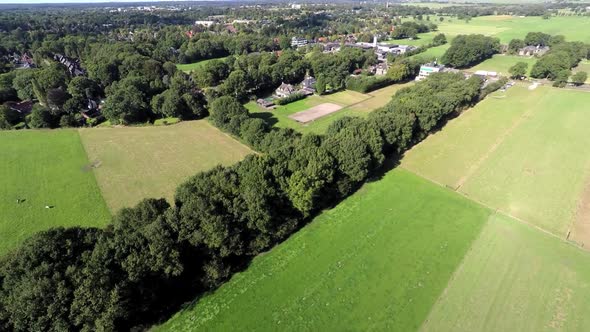 Aerial footage of green meadows with a rural town in the background.