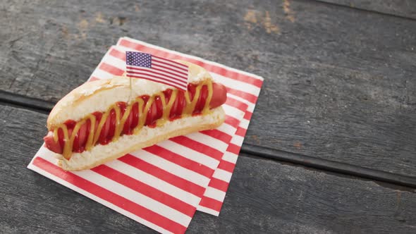 Video of hot dog with mustard and ketchup with flag of usa on a wooden surface