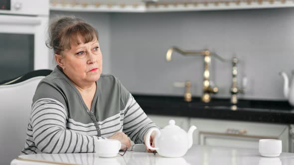 Reflective Middle Aged Woman Taking Off Glasses Thinking About Problem During Drinking Tea