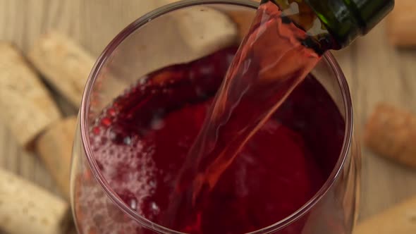 Wine is poured into a glass on the background of wine corks.