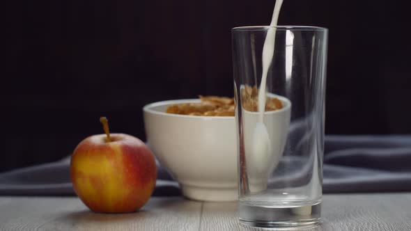 Pouring Milk Into a Glass Glass on a Wooden Table