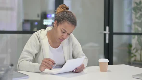 African Woman Reading Reports While Sitting in Office