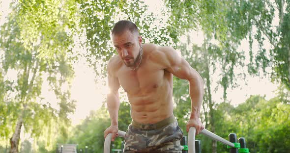 Handsome Bodybuilder Performing Exercise on Parallel Bars Alone