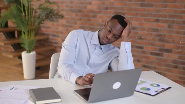 Upset Bored African American Man Freelancer or IT Specialist Works in the Office Sitting at a Desk