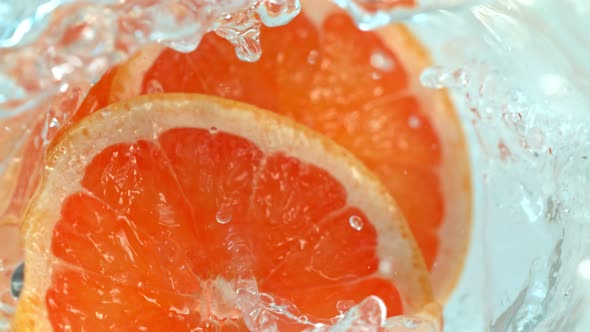 Super Slow Motion Shot of Falling Grapefruit Slices Into Water Vortex at 1000Fps