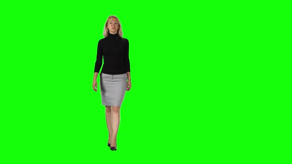 Blonde Girl in Black Turtleneck, Grey Skirt and High Heel Shoes Going Against Green Screen.