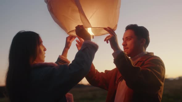 Couple starts the Chinese lantern at sunset