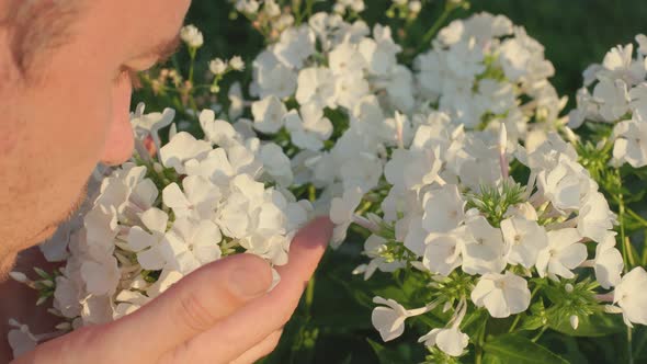 A Man Smells Flowers in the Garden