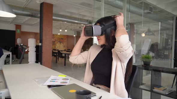 Businesswoman sitting at desk using virtual reality simulator