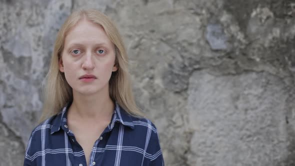 Portrait of Unhappy Woman Wearing Shirt Looking To Camera. Close Up View of Sad Person with Blue