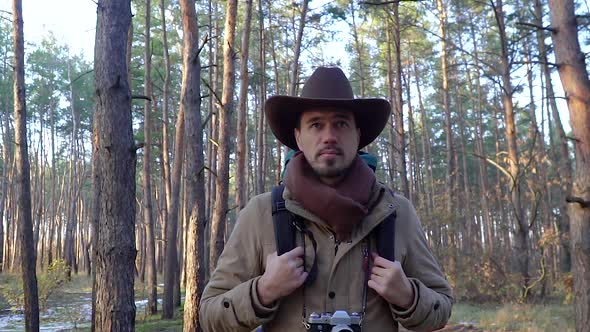 A Man with Camera Walks Along a Trail in the Forest