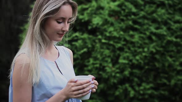 Beautiful Girl Stands on the Street with a Cup