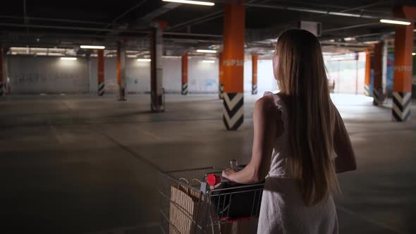 Woman Walking with Shopping Cart Through Parking