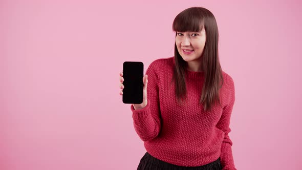 Smiling White Darkhaired Woman Wearing Red Sweater Holding Black Screen Smartphone Up to Camera and