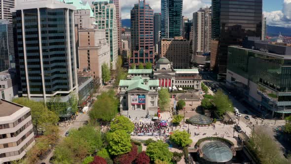 Drone shot pulls away from crowd of people on the steps of Vancouver Art Gallery in Robson Square in
