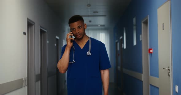 A Doctor is Talking on a Mobile Walking Along the Corridor of the Medical Center