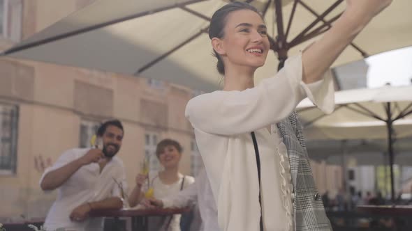 Woman Making Photo On Phone With Friends On Background