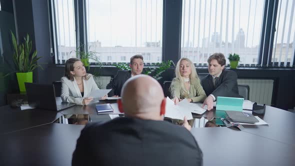 People Discussing Business Project at Conference Table Passing Documents to Male CEO