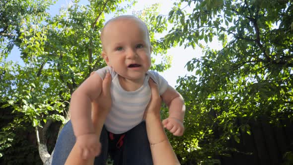 POV of Mother Lying on Grass and Lifting Up Her Smiling Baby Boy in Park