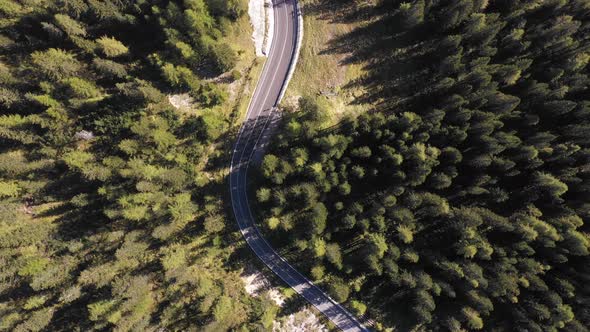 Aerial top view of mountain road through the wood