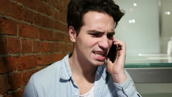 Angry Young Man Talking on Mobile Phone, Discussing an Issue