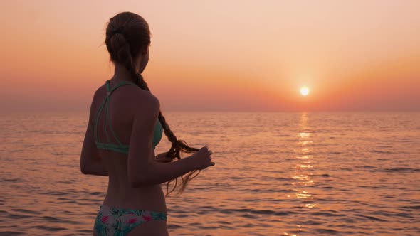 The Girl Is Standing on the Seashore Thoughtfully Plaiting Braids Looking Into the Distance