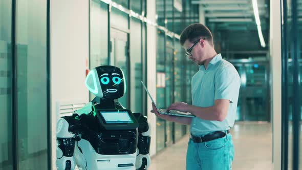 A Man is Using a Laptop to Communicate with a Robot