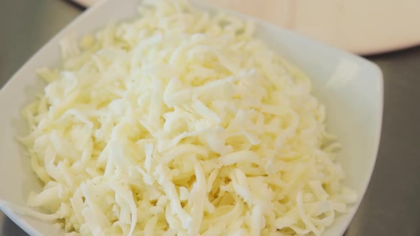 close up of freshly shredded mozzarella in a bowl. natural ingredients for pizza. slow motion