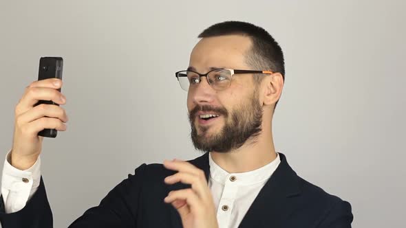 A Young Successful Businessman Is Talking with Partners in a Video Chat on His Smartphone