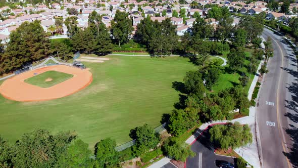 Aerial drone pan over and by a baseball field at a community park in the suburbs.