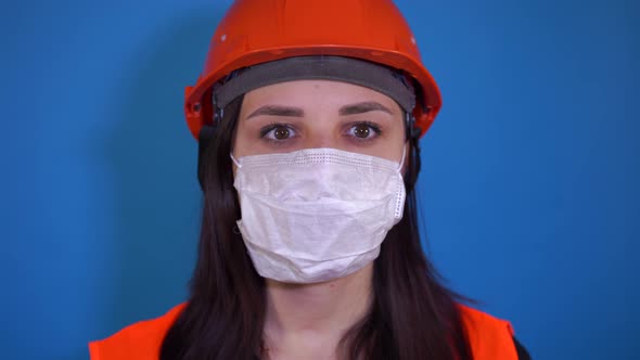 Portrait of Young Woman in Medical Mask on Her Face on Blue Background