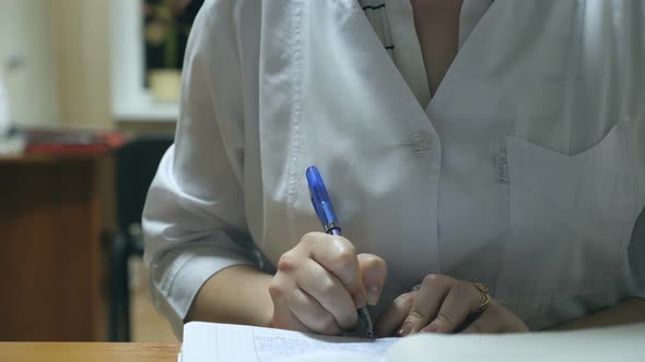 Young Nurse Working at Office Desk and Writing Medical Records