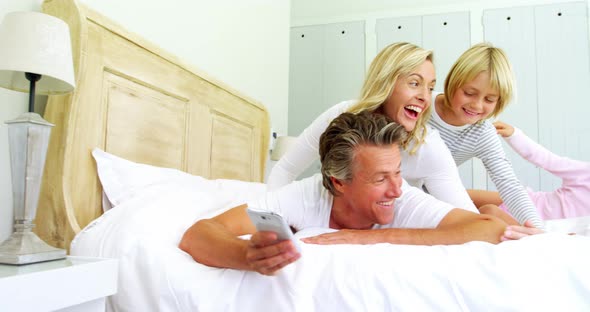 Happy family taking a selfie on mobile phone in the bed room 4k