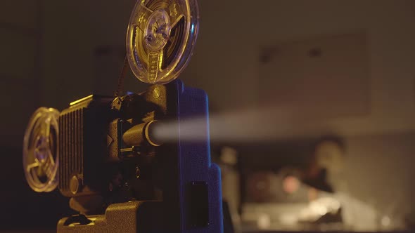 Old fashioned movie projector and film screening in a dark room with colorful lights