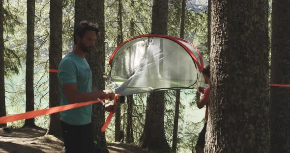 Two Men Setting Hanging Tent Camping in Sunny Forest Near Lake