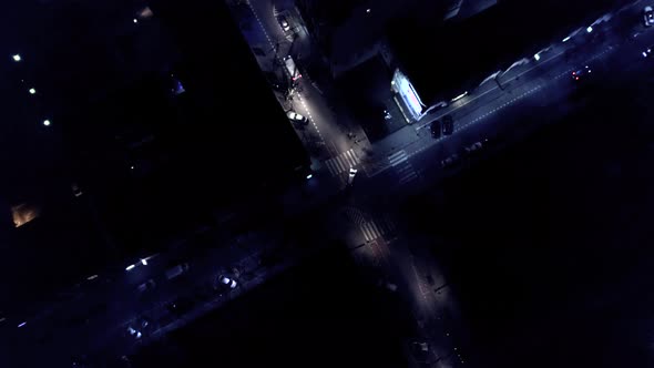 Vertical top down aerial view of traffic on street intersection at night. Cars driving. 4K UHD