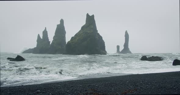 The Black Sand Beach of Reynisfjara with Waves Hitting the Shore on Foggy Rainy Stormy Day