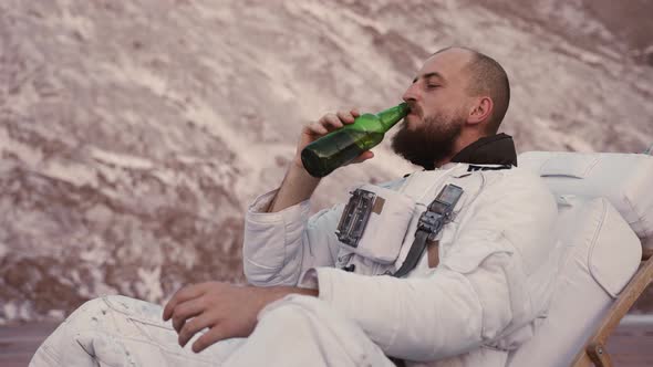 an Astronaut Without a Helmet in a Chair Drinks Beer and Chill