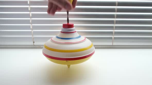 Child toy on background of blinds, untwisted by hand of whirligig.