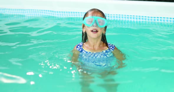 Little Girl in Goggles Having Fun Dives and Swim in the Swimming Pool